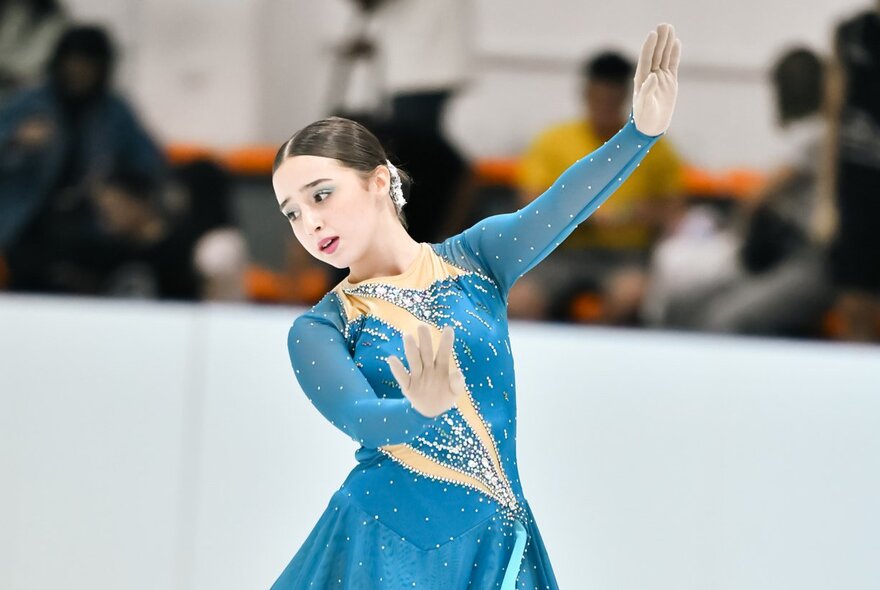 A young female figure skater in a blue skating costume.