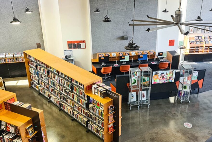 Looking down on the interior of a library with pendant lighting and a large ceiling fan.