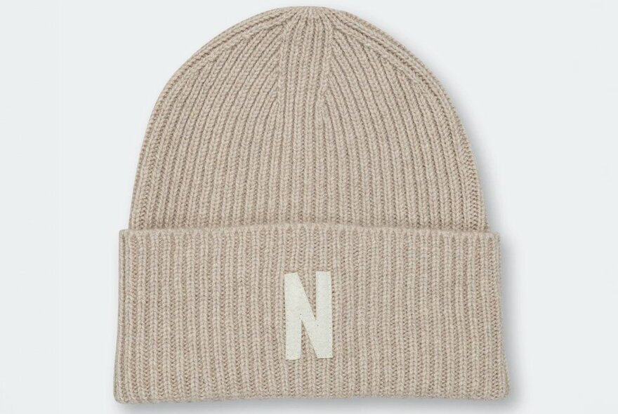 A beige ribbed beanie with the letter 'N' on the cuff.