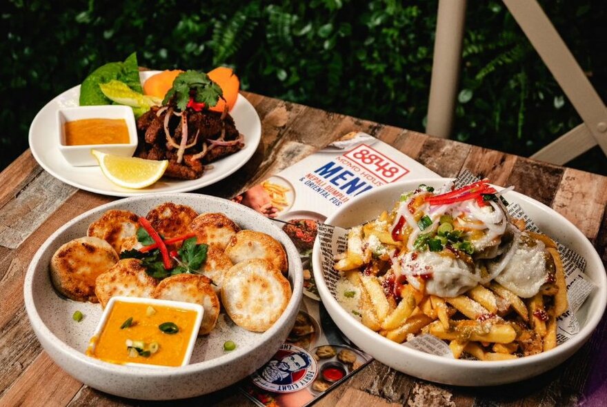 Three plates of Nepalese food on a table, with menus resting underneath.