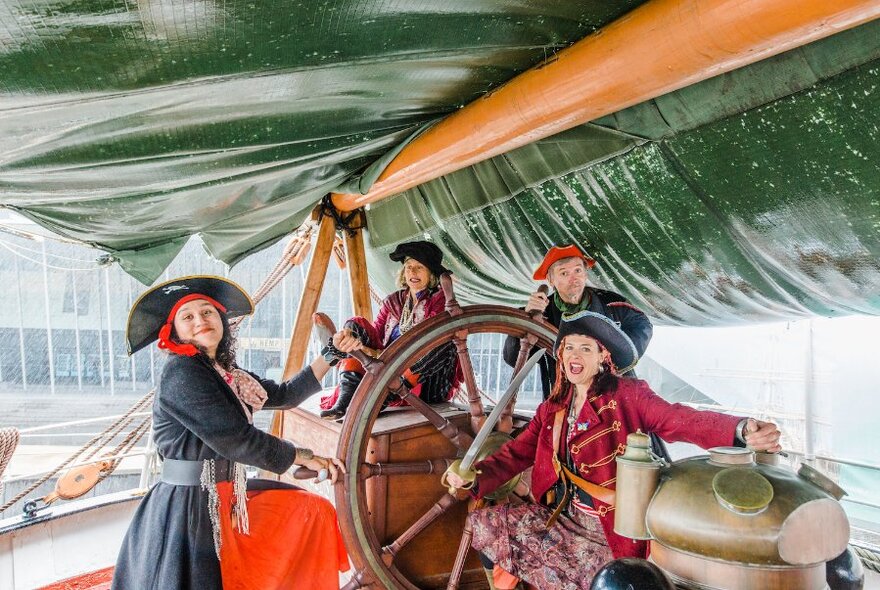 A group of people dressed at pirates posing on an old ship.