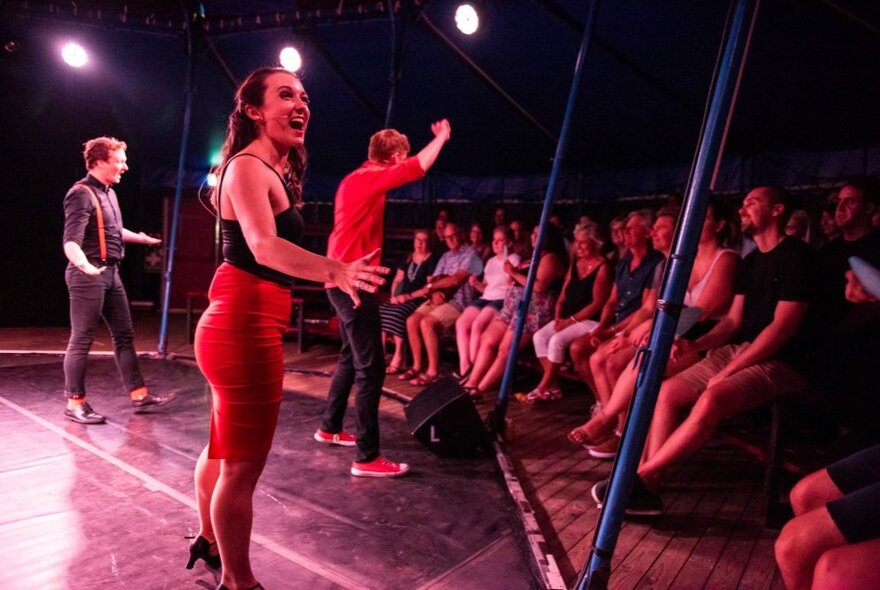Members of the Impromptunes cast on stage performing to an audience.