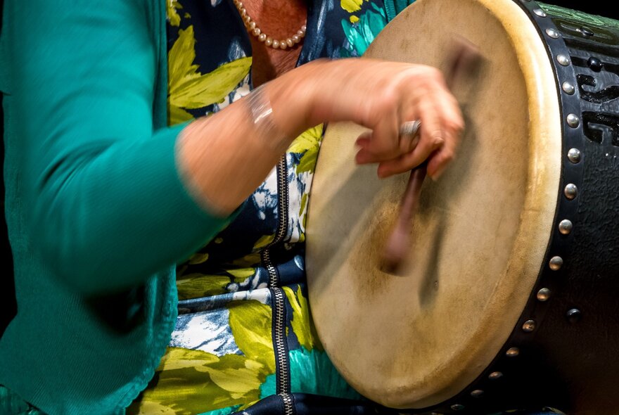 Hand holding and playing a traditional Irish drum.