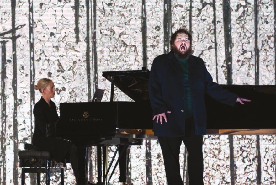 Singer standing next to a pianist and grand piano.