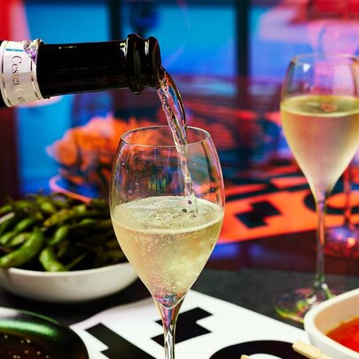 A bottle of wine being poured into a wine glass.