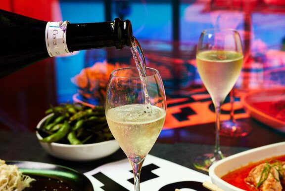 A bottle of wine being poured into a wine glass.