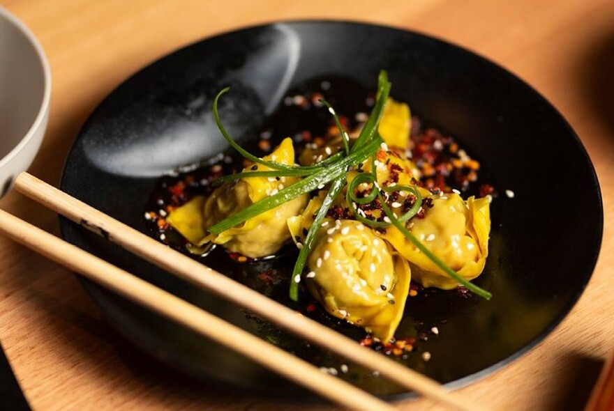 A plate with dumplings and resting chopsticks.