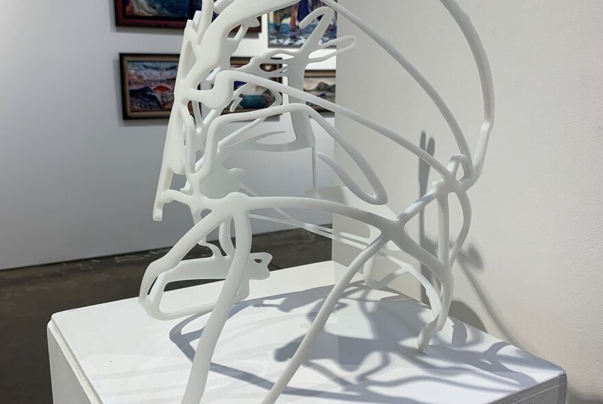 A white sculpture on a display plinth in a gallery.