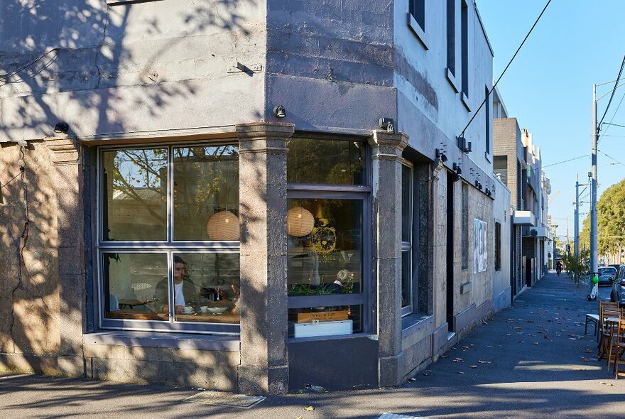 The exterior of a concrete corner cafe. 