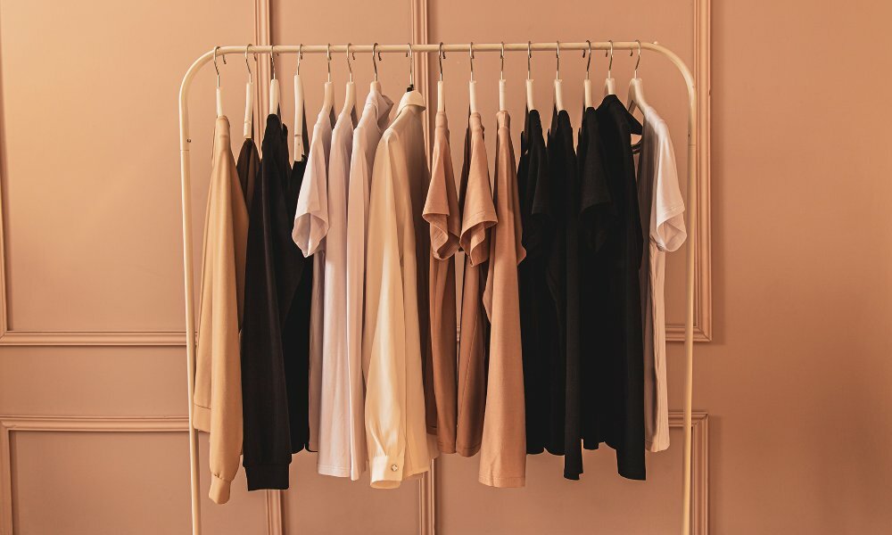 A rail of neutral coloured basic clothing.
