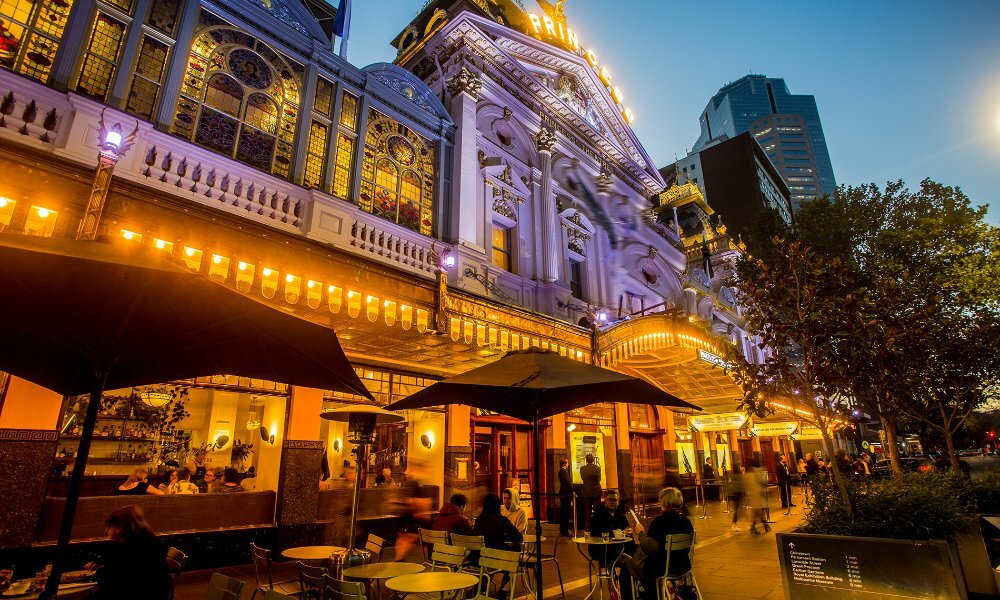 People dining outside a theatre in the evening.