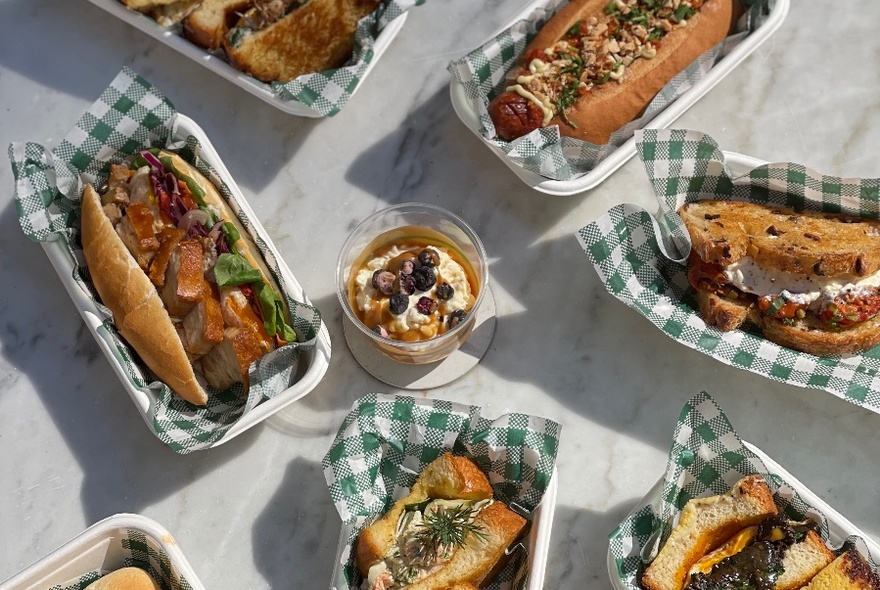 Selection of sandwiches in green and white serviettes, on a table, seen from above.