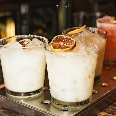 Assorted flavoured margaritas cocktails on a bar.