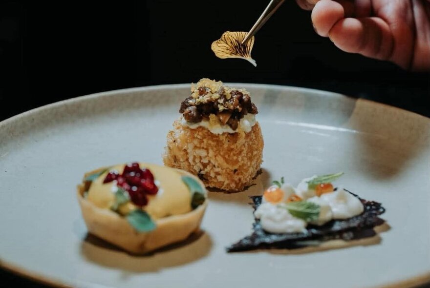 A chef placing an edible flower petal on a canape.