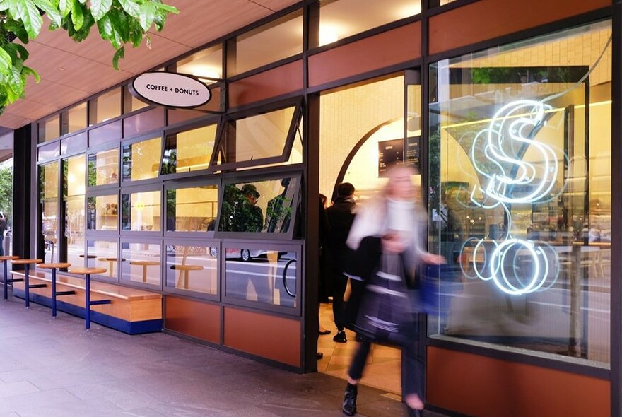 Person walking past a doughnut shop.