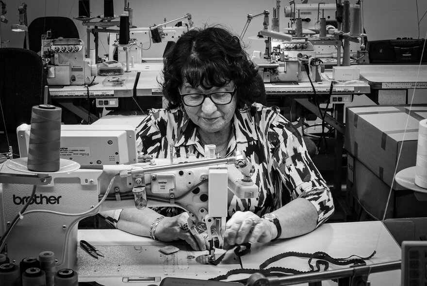 A black and white image of a woman at a sewing machine.
