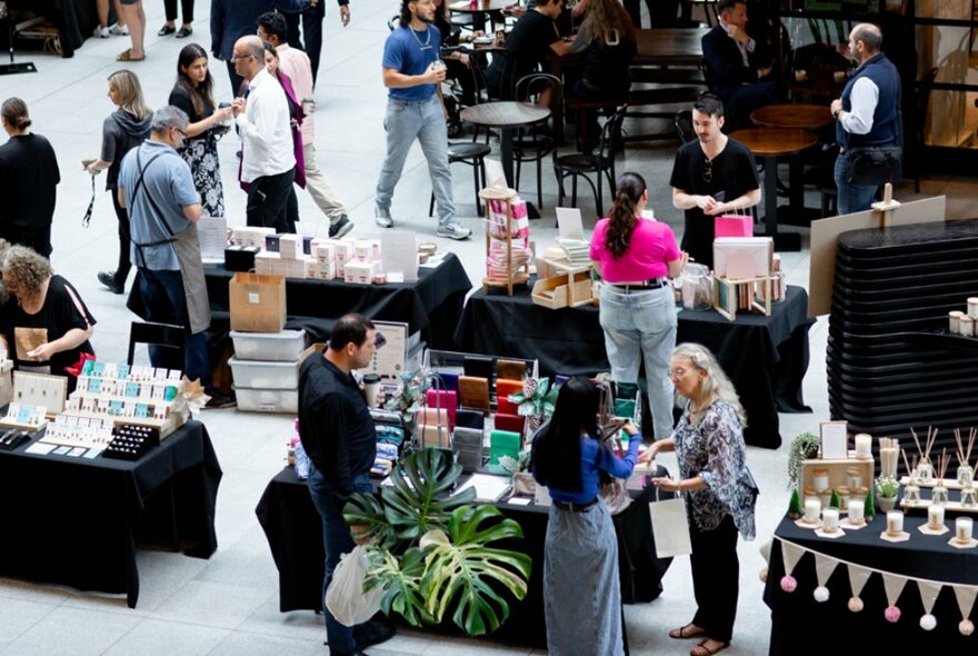 People wandering around a indoor plaza browsing at different market stalls.