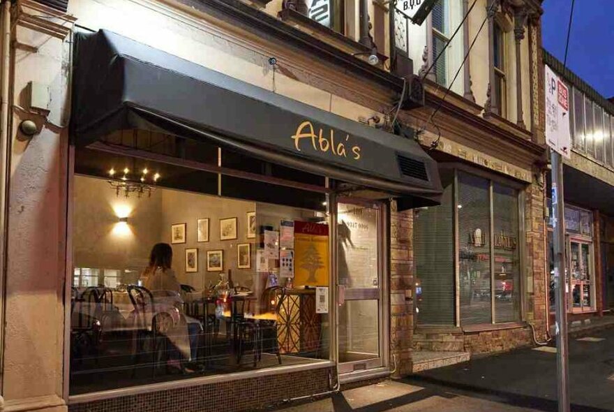 A woman sitting in the window of an old-fashioned restaurant