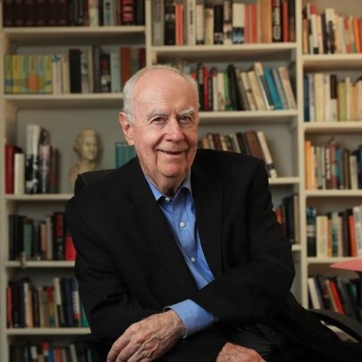 Portrait of political commentator Paul Kelly in front of a wall of bookshelves.