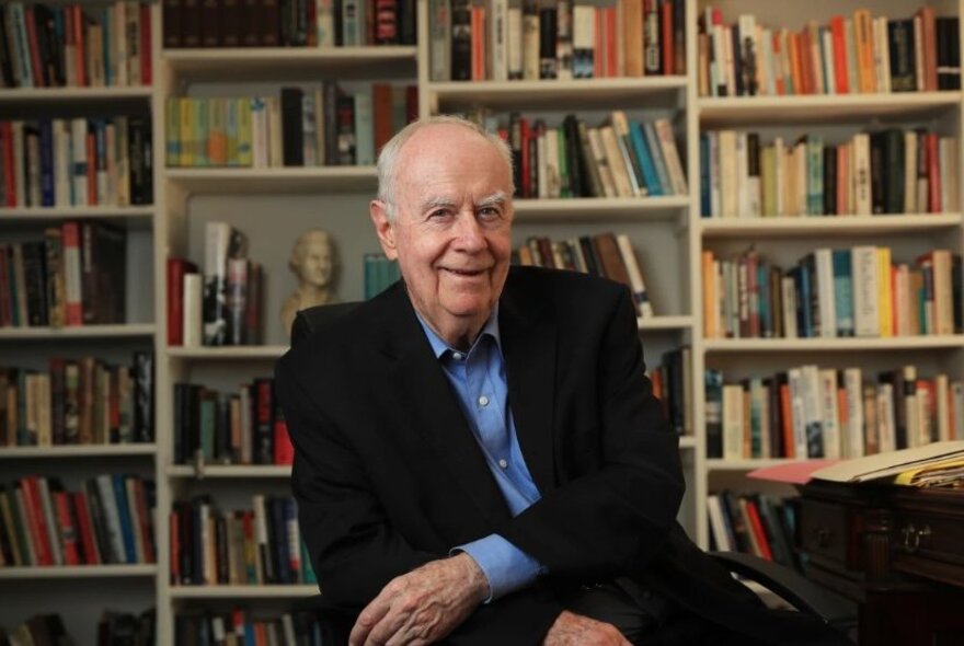 Portrait of political commentator Paul Kelly in front of a wall of bookshelves.