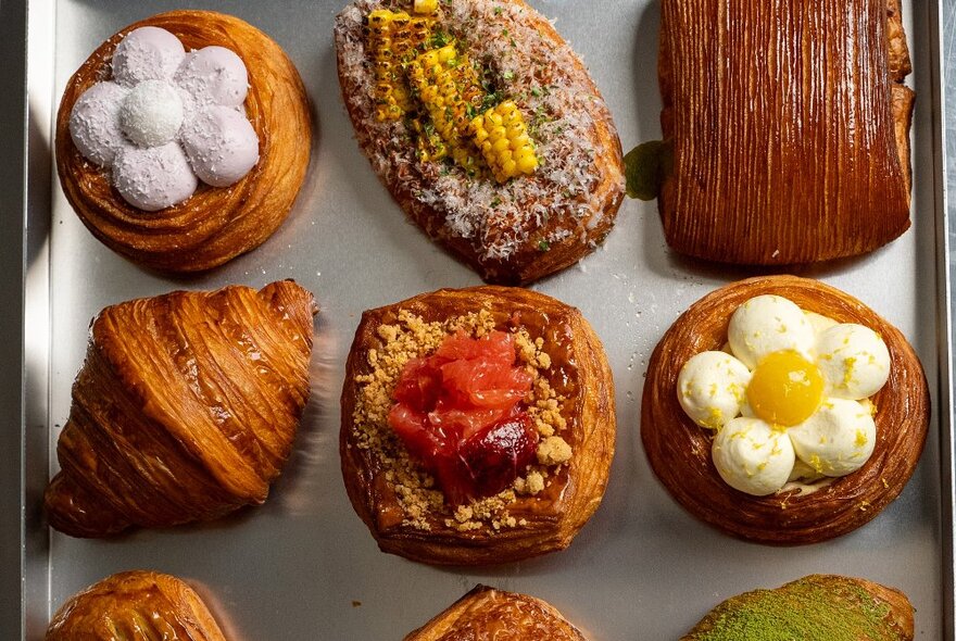 A tray of decorated pastries with corn, fruit and flour patterns.
