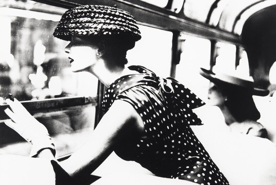 A black and white photograph of a glamorous young woman wearing a silk polka dot dress and bonnet, circa 1930.