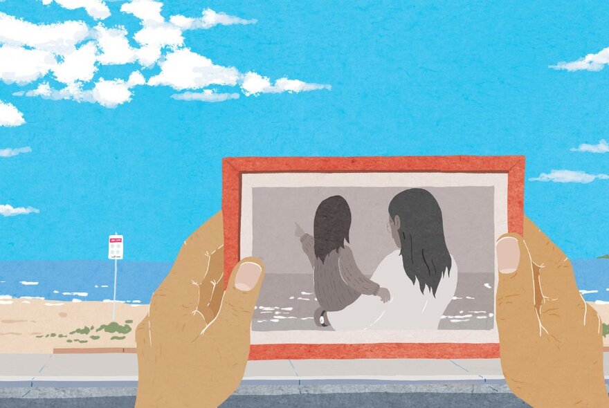 A graphic representation of two hands holding a picture frame in front of a beach with blue sky, a black and white picture of a mother and her child in the frame.
