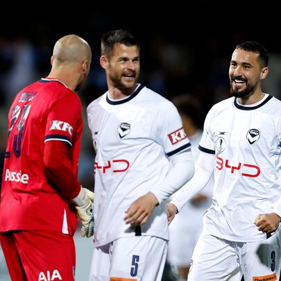 Two Melbourne Victory A-League players talking with a Melbourne City player on the field.