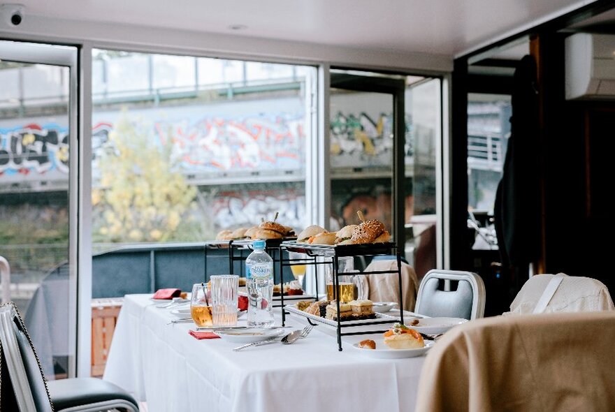 A restaurant table dressed for dinner on board a boat, with graffitied walls in the background.