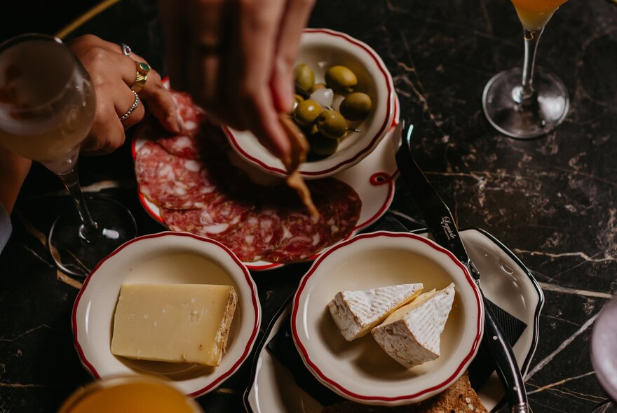 Looking down on a small plates of salami, cheese and olives. 