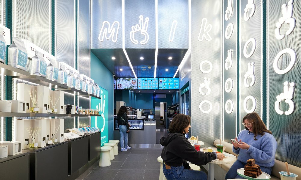 Two friends are sitting in a neon-lit cake shop