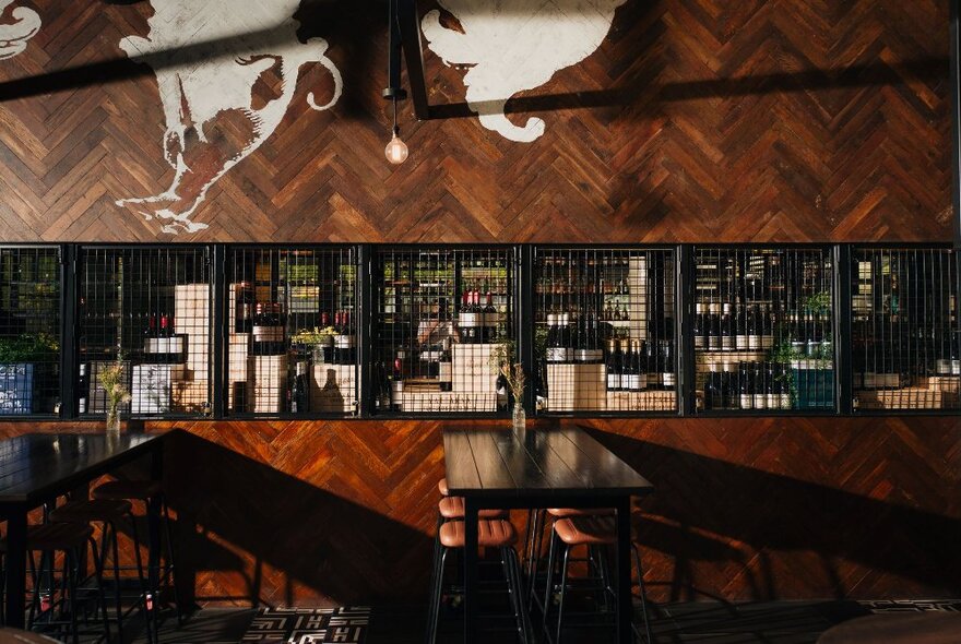 A timber-lined bar with dark bar tables in front.