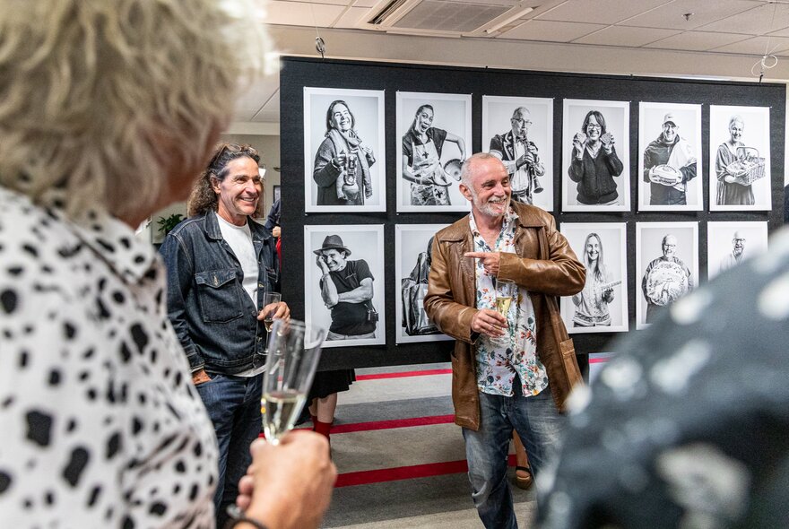 Presenters standing in front of a series of portraits displayed on wall dividers.