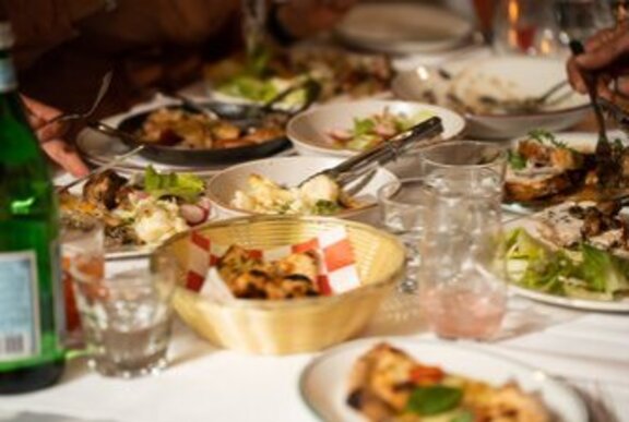 A selection of Italian dishes laid out on a table with a sparkling water and glasses.