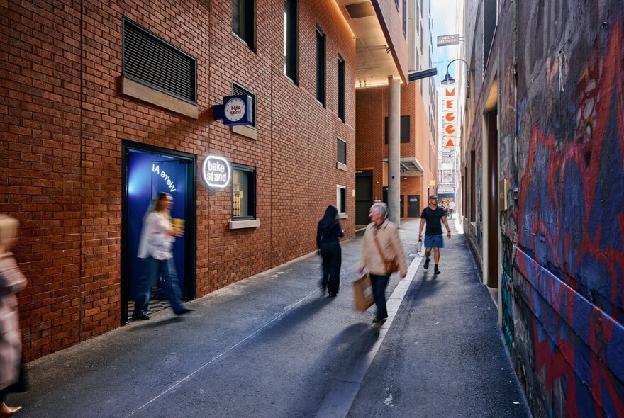 A Melbourne city laneway, with blurred pedestrians walking along it and past the exterior of BakeStand, a small bakery.