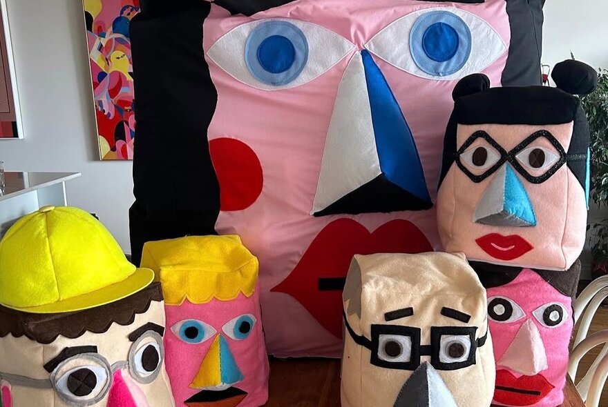 A group of fabric faces, some with glasses, in different sizes. 