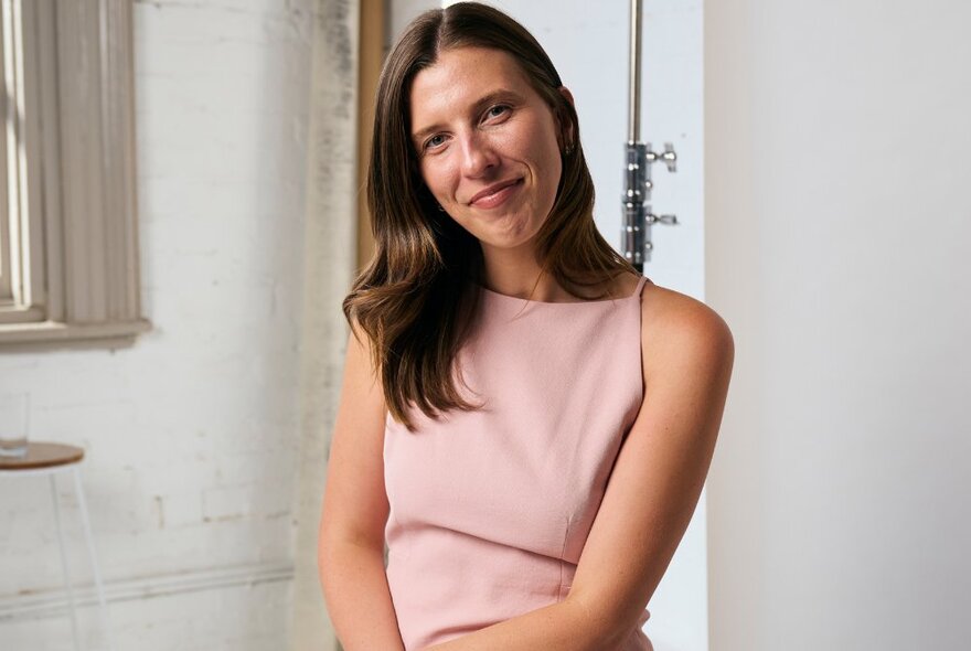 Journalist Hannah Ferguson smiling and wearing a pink sleeveless dress.