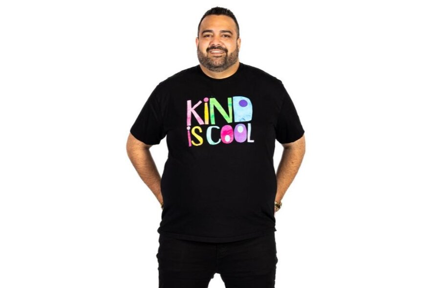 Comedian Dane Simpson, wearing a T-shirt with 'kind is cool' logo.