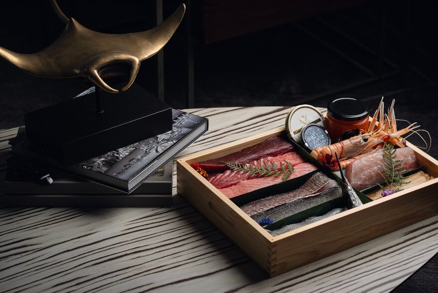 A wooden tray with small pieces of raw fish displayed in it, sitting on top of a counter.