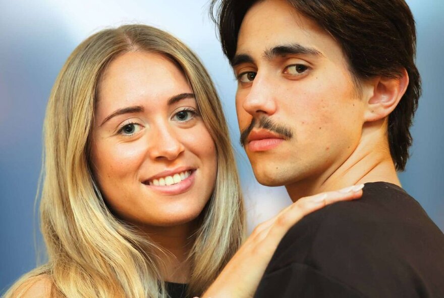 Blonde and dark-haired actors playing the lead roles in Grease.