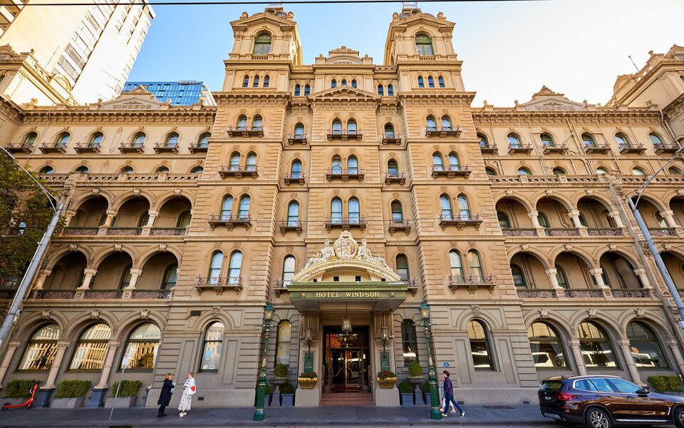 People walking into a grand seven-storey hotel in the city.
