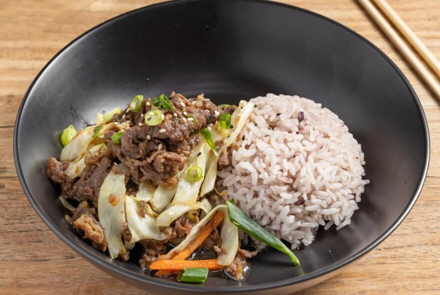 Korean Bulgolgi, a stir-fried beef dish with brown rice served in a black bowl.