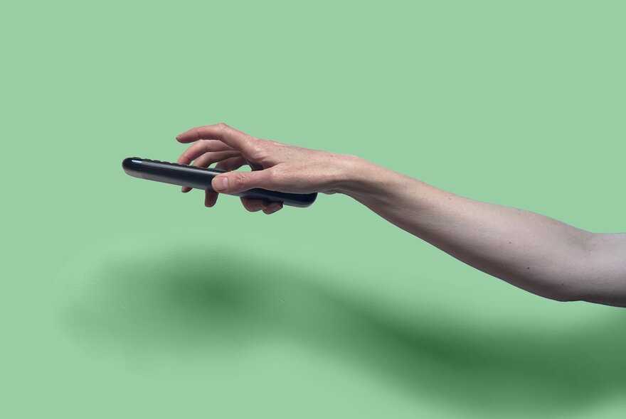 An outstretched hand holding a remote.