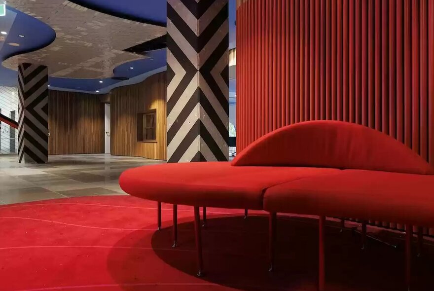 Red banquette seating and red carpet in an open lounge area in the Koorie Heritage Trust building.