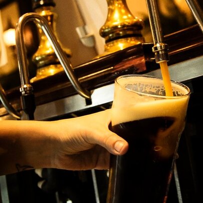 A hand pouring Guinness into a glass from a tap. 