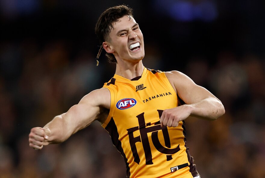 Hawthorn AFL football player with arms outstretched during a match.