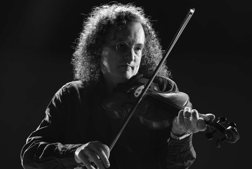 A dark black and white image of Irish fiddler, Martin Hayes.