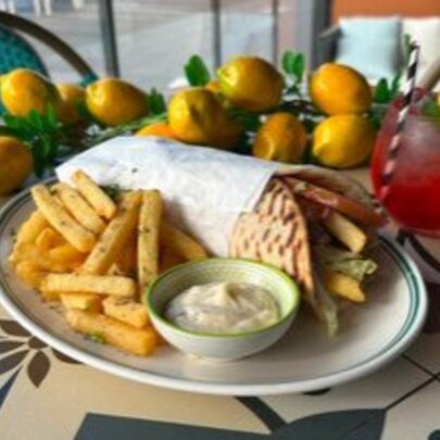 Plate of souvlaki and chips with dip surrounded by lemon ornaments.