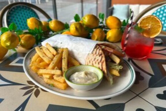 Plate of souvlaki and chips with dip surrounded by lemon ornaments.