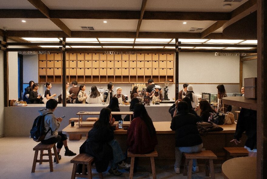 Customers seated at a large bench table at a Japanese Matcha store.